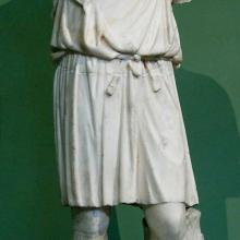 Exomis, Kopie einer Statue aus dem 4. Jhd. Quelle: https://upload.wikimedia.org/wikipedia/commons/f/f0/Young_man_exomis_Musei_Capitolini_MC892.jpg